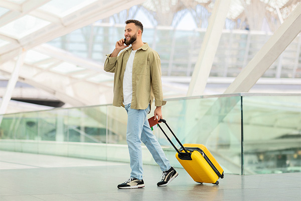 Un hombre hablando por teléfono y con su equipaje de mano en un aeropuerto