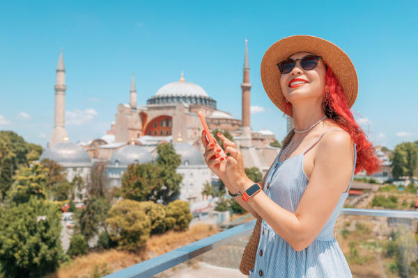 Mujer viajera con smartphone en un día soleado en la plaza Sultanahmet con la mezquita de Santa Sofía al fondo, Estambul, Turquía