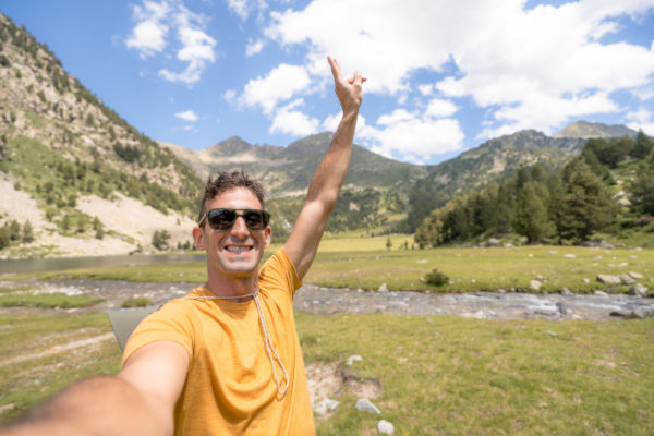 Hombre tomándose una selfie en un valle de los Pirineos, rodeado de montañas y naturaleza.