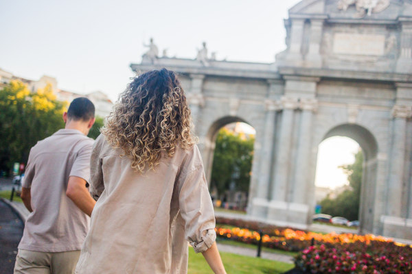 Pareja de turistas caminando hacia la Puerta de Alcalá, Madrid, España.