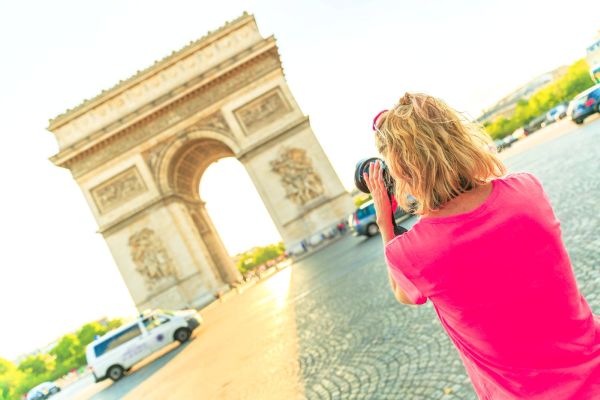 Mujer tomando una foto del Arco del Triunfo en París.