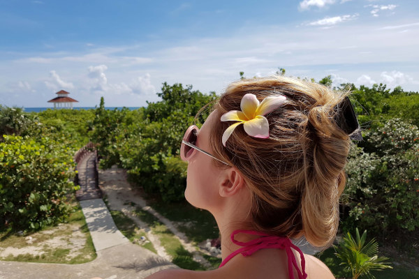 Mujer joven mirando hacia el mar desde un sendero rodeado de vegetación en el Cayo Santa María, Cuba.