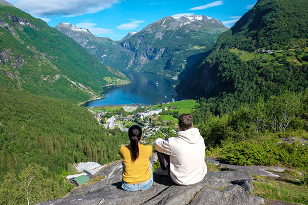 Pareja observando los fiordos noruegos desde una roca en las alturas