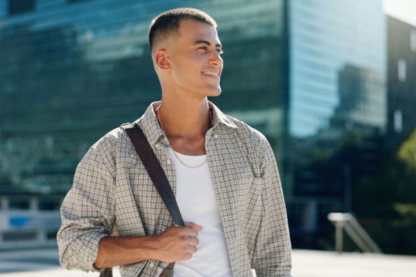 Joven uruguayo con mochila de estudiante, orgulloso en el campus universitario donde realiza su intercambio.