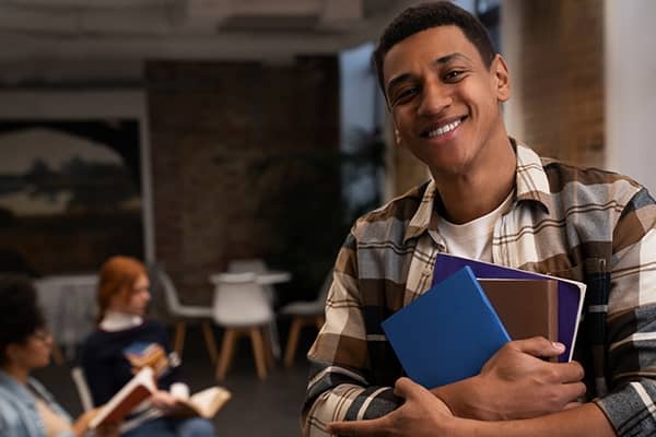 Estudante em sala de aula no intercâmbio segurando livros e cadernos.