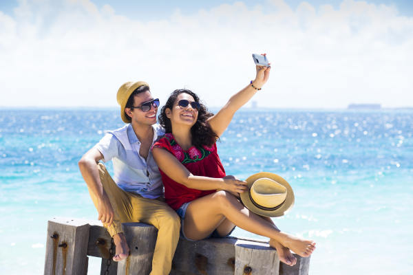 Pareja tomándose una selfie con un smartphone en una playa de Isla Mujeres, México.