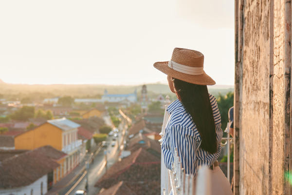 Mujer viajera en un balcón colonial mirando desde arriba la ciudad de Granada, Nicaragua, al atardecer
