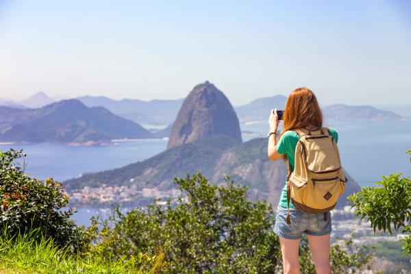 Mujer turista con mochila sacando foto con smartphone del Pan de Azúcar en Río de Janeiro, Brasil.