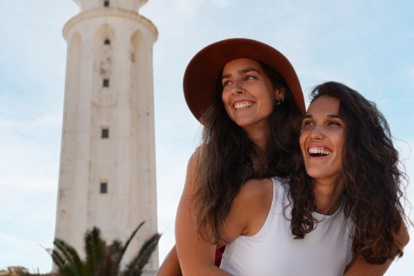 Dos mujeres posando con un faro de fondo