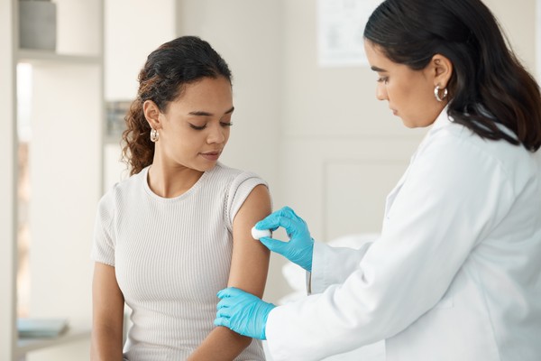Médica limpiando con un algodón una zona del brazo para una inyección.
