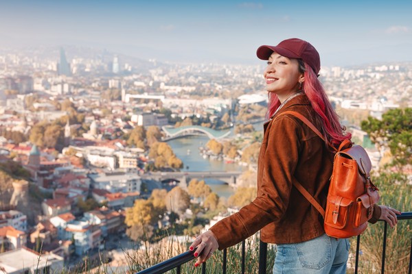 Mujer con mochila admirando el paisaje urbano panorámico de Tiflis, Georgia, desde un punto de vista alto.