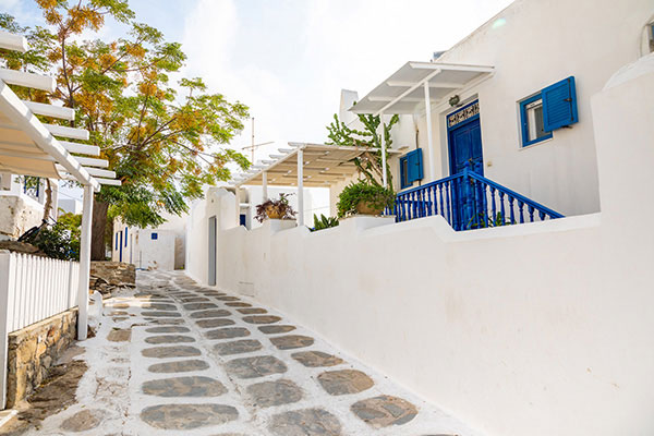 Calle empedrada de Mykonos con casa de piedra blanca