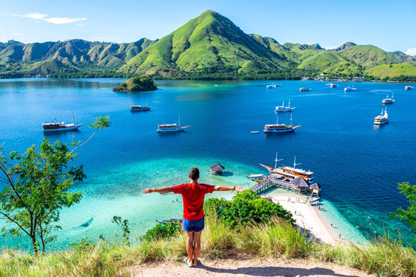 Turista observando el paisaje de Komodo con brazos abiertos