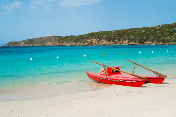 Dos botes rojos con remos en la playa de Tuerredda, Cerdeña, en un día soleado.