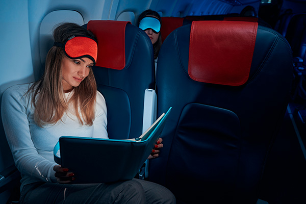 Mujer leyendo un libro en el avión por la noche