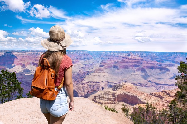 Mujer de excursión en el South Rim del Gran Cañón con vistas hacia las formaciones rocosas desde la altura.