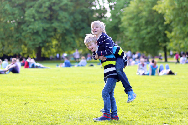 Niños riéndose y jugando en el parque de Hyde Park durante una tarde soleada.