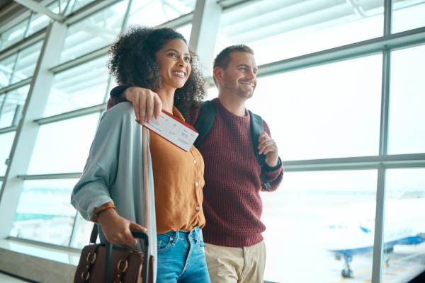 Pareja feliz con maleta y tarjeta de embarque en el aeropuerto