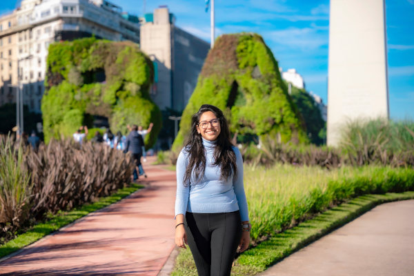 Mujer sonriendo frente al icónico Obelisco y el jardín vertical “BA verde” en la Plaza de la República, Buenos Aires, Argentina.