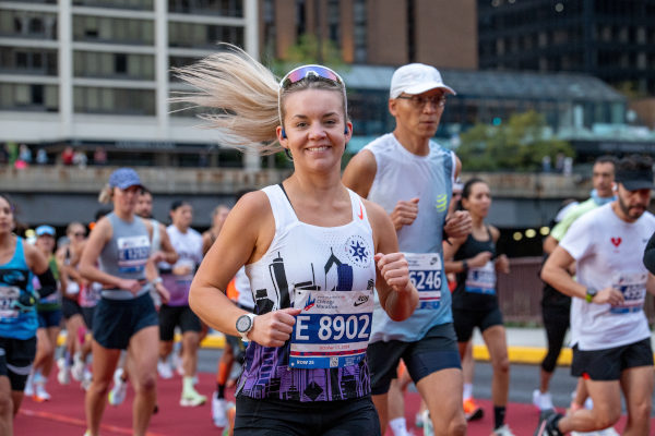 Mujer atleta sonriendo mientras corre el Maratón de Chicago, con otros atletas de fondo