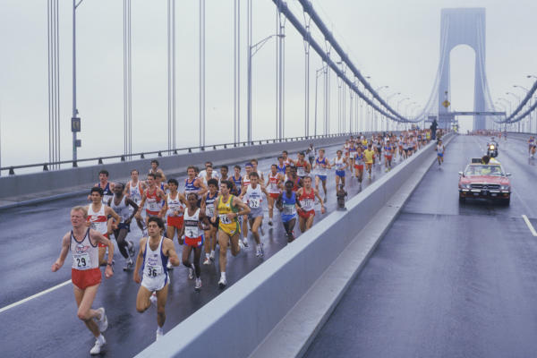 Vista de corredores cruzando el Puente Verrazano-Narrows al inicio del Maratón de Nueva York en un día nublado.