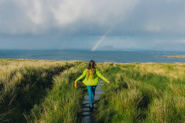 Mujer caminando en la isla Runde bajo un arco iris