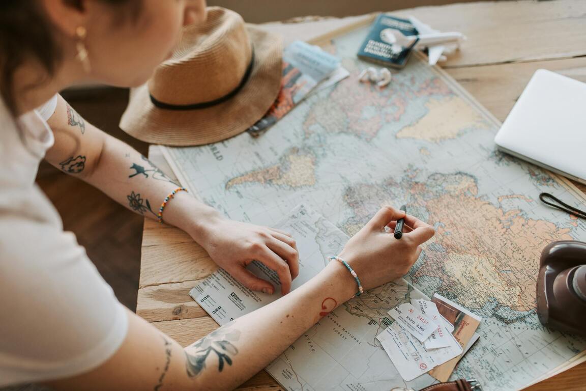Pessoa planejando roteiro sobre mapa-múndi com passagens e documentos à mesa, simbolizando a escolha do melhor seguro viagem internacional 2025