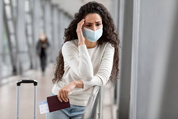 Mulher em aeroporto usando máscara descartável de covid antes de embarcar.