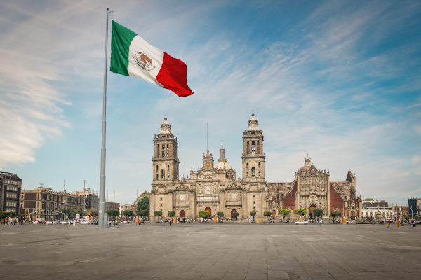 Bandera mexicana ondeando en Plaza Zócalo con la Catedral de Ciudad de México de fondo