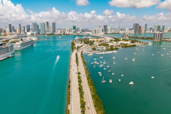 Vista aérea del centro de Miami y su bahía, con cruceros y veleros navegando en aguas turquesas.