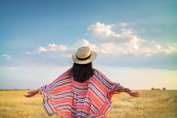 Mujer andina con los brazos abiertos en un campo en un día soleado.