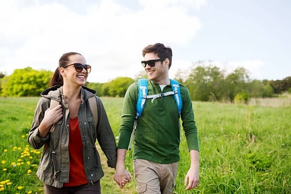 Casal de viajantes felizes em dia ensolarado caminhando de mãos dadas.