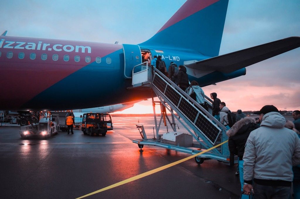 Passageiros embarcam em avião ao pôr do sol, ilustrando artigo sobre a Convenção de Montreal em voos internacionais.