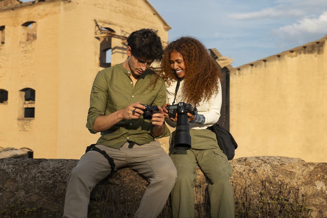 Casal composto por homem e mulher observa fotos em suas câmeras profissionais diante de uma construção antiga, ilustrando artigo de blog da Assist Card sobre o que fazer no México