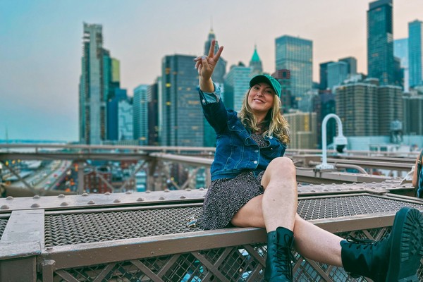 Mujer turista en el puente de Brooklyn en Nueva York al atardecer.