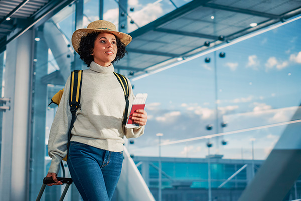 Mujer en terminal de aeropuerto con boletos en mano