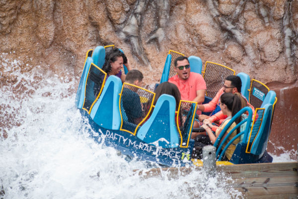 Grupo de personas disfrutando una atracción acuática en Disney World Orlando, durante un paseo en bote circular con caídas de agua.