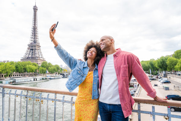 Pareja feliz tomándose una selfie con la Torre Eiffel en París de fondo.