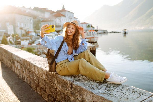 Mujer turista tomándose una fotografía tipo selfie en un mirador en un día soleado.