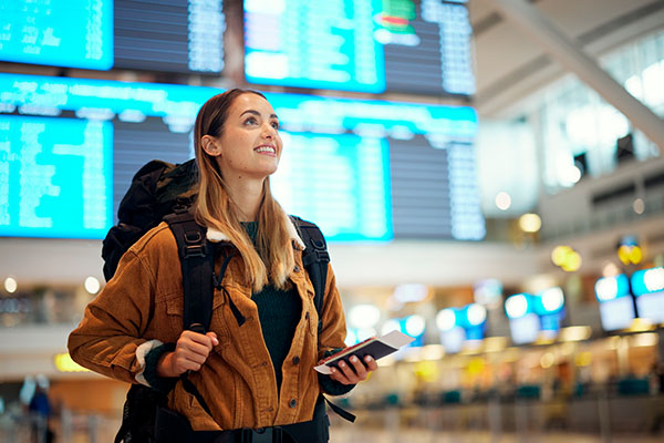 Mujer en el aeropuerto con equipaje y documentos en mano