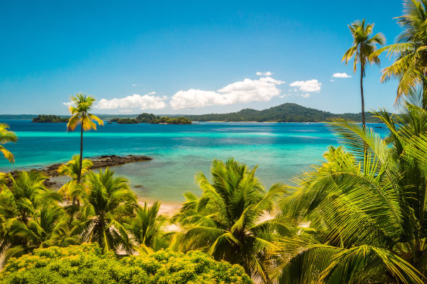 Vista de la playa y aguas cristalinas de la Isla Coiba entre la vegetación en un día soleado.