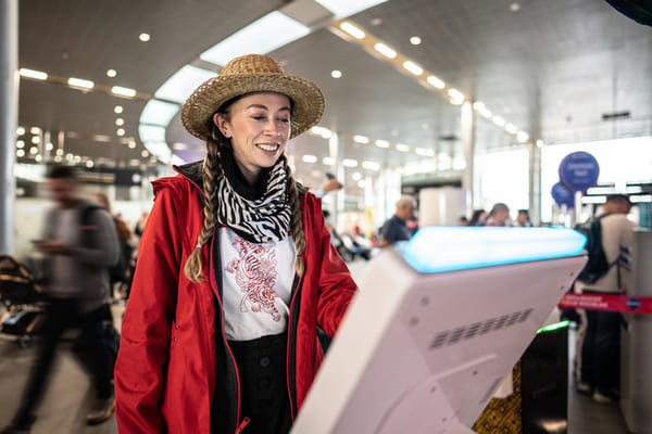 Mujer que utiliza la máquina de autoservicio de check-in en el aeropuerto