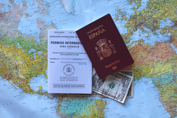 Permiso internacional de conducir y pasaporte español, sobre un mapa y algunos dólares.