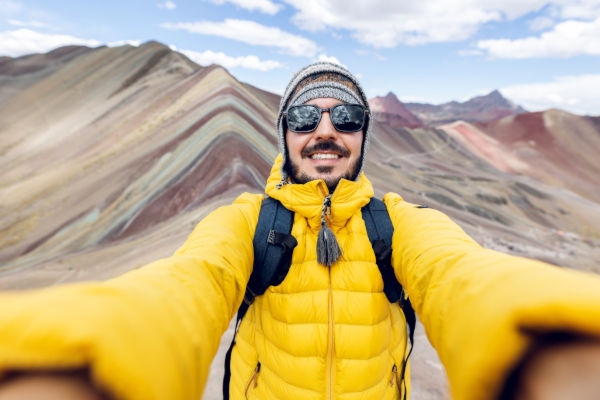 Viajero tomándose una selfie en la Montaña de Siete Colores (Vinicunca), luciendo ropa de abrigo.