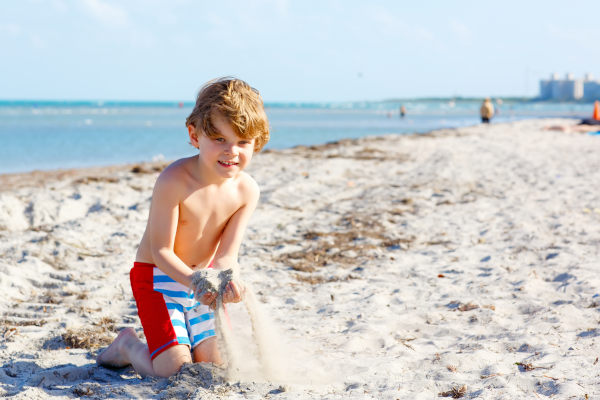 Niño pequeño jugando con la arena en Key Biscayne en un día soleado