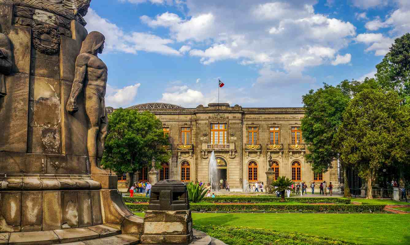 Imagem do Castelo de Chapultepec com jardins bem cuidados, fonte e fachada neoclássica, um destaque entre os pontos turísticos do México