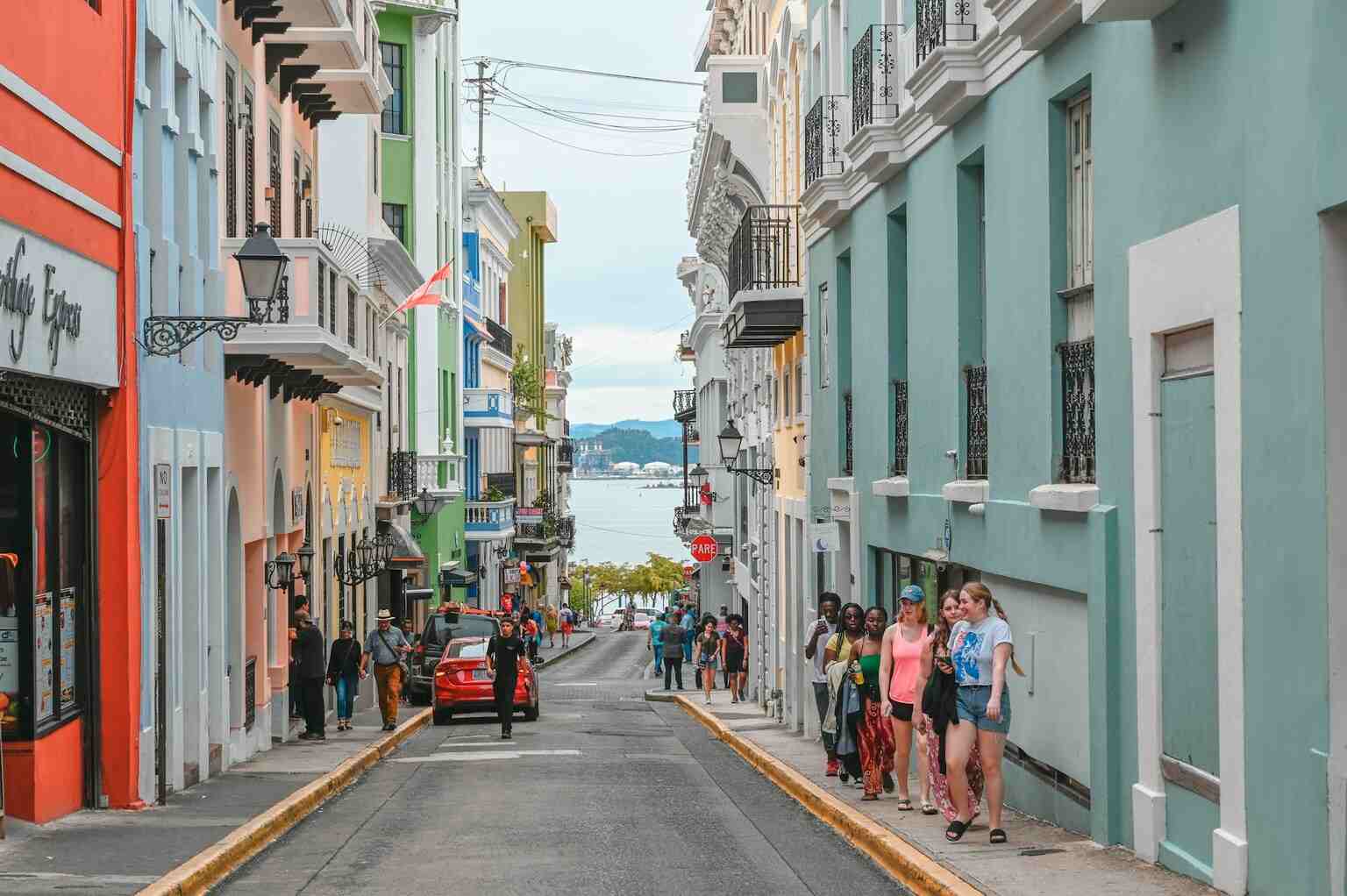 Turistas caminham por rua com prédios coloniais em Old San Juan em foto que ilustra artigo sobre viagem para Porto Rico 2025.