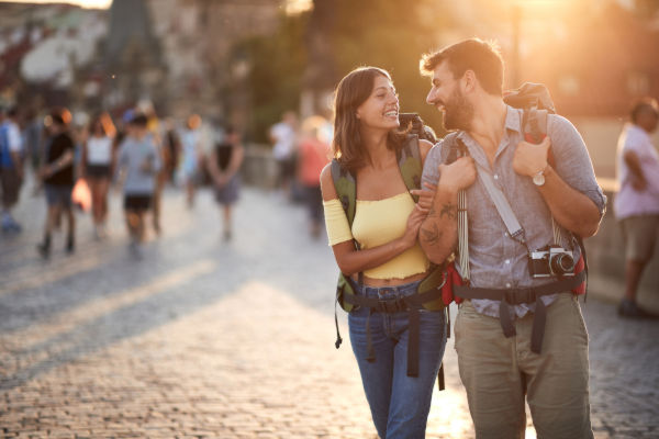 Pareja de turistas caminando al atardecer sobre el Puente de Carlos, uno de los lugares más visitados de Praga.