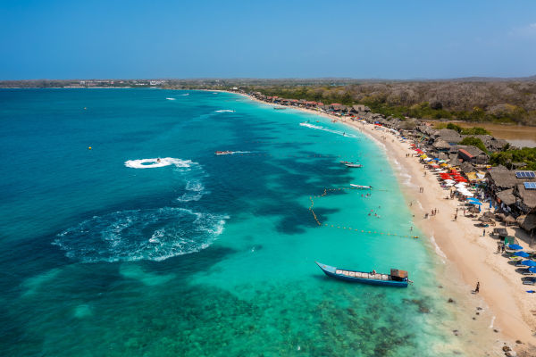 Vista aérea da movimentada praia de Playa Blanca, na ilha de Barú, perto de Cartagena, Colômbia, com mar turquesa do Caribe e areia branca.