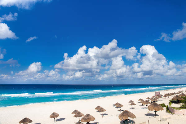 Praia de areia branca e mar turquesa em Cancún, México, na Playa Delfines, com ondas suaves e paisagem tropical.